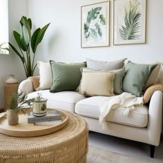 a living room with white couches and green pillows on top of the sofas