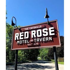 the sign for red rose motel and tavern is in front of some trees on a sunny day