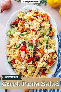 a bowl filled with pasta salad next to lemons and other food on the table