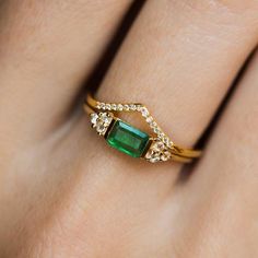 a woman's gold ring with an emerald and diamonds