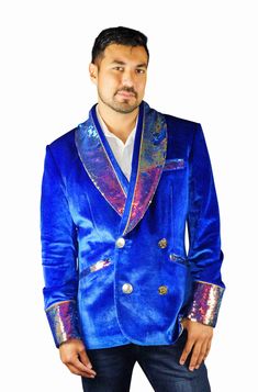 This mens royal blue velvet smoking jacket exudes a certain sophistication that other jackets can only dream of. We have taken this perfectly tailored,double breasted blazer to the next level with the addition of iridescent multi color flip sequins. FEATURES: Double breasted Fully lined with our signature satin 4 pockets including 1 inside breast pocket Reversible iridescent sequin contrast collar, cuffs and trim Velvet trimmed collar to for ultimate comfort Ethically made in-house in our studio Royal Fitted Blazer For Party, Single Breasted Velvet Suit For Party, Luxury Velvet Outerwear For Party, Single-breasted Velvet Suit For Party, Party Velvet Single-breasted Suit, Winter Party Blue Blazer, Velvet Party Suits For Winter, Blue Party Outerwear With Lapel Collar, Winter Velvet Party Suits