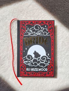 a book that is laying on top of a white blanket with a red string attached to it