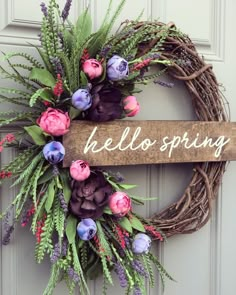 a wreath that says hello spring hanging on a door with purple flowers and greenery