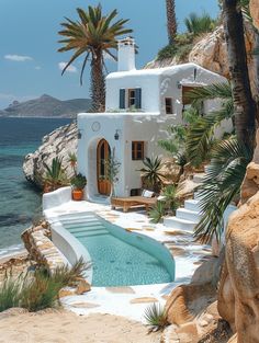 an outdoor swimming pool next to the ocean with palm trees in front of it and a white house