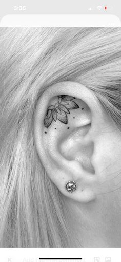 a woman's ear has a flower tattoo on it