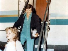 an old photo of a man and woman exiting a plane with luggage on the stairs