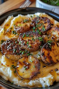 a plate with mashed potatoes and meat on it, garnished with chives