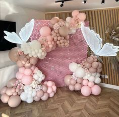 balloons are arranged in the shape of flowers and birds on a pink backdrop with white wings