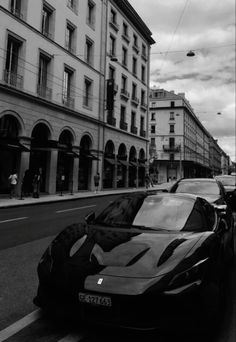 a black and white photo of a car parked on the side of the road in front of some buildings