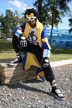 a man sitting on top of a pile of rocks wearing a yellow and blue costume