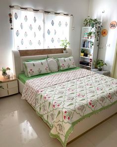 a bedroom with a bed, bookcases and plants in the window sill