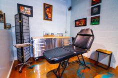 a black leather chair sitting on top of a hard wood floor next to a metal cabinet