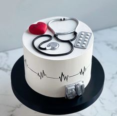 a white cake with a stethoscope on top and a red heart in the middle