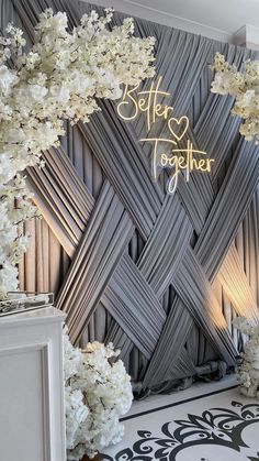 a room decorated with white flowers and silver wallpaper that says better together on it