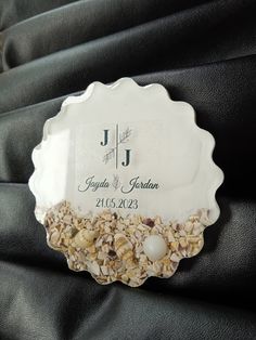 a personalized glass plate with shells and pearls on the bottom sits atop a black fabric