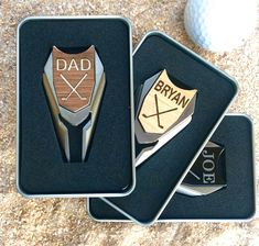 three personalized golf club and ball markers in tins