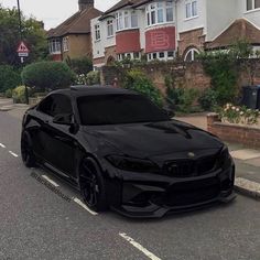 a black car is parked on the side of the road in front of some houses