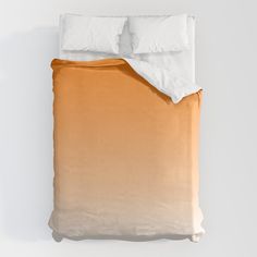 an orange and white ombreed comforter with two pillows on the bottom half