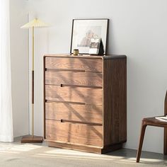 a wooden dresser sitting next to a chair in a room with a lamp on top of it