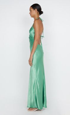 a woman in a long green dress looking back at the camera with her hand on her hip