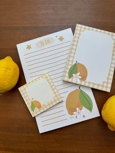 three lemons and two notepads sitting next to each other on a table