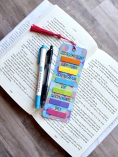 an open book with pens and magnets on it sitting next to a marker pen