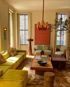 a living room filled with yellow couches next to two windows and a coffee table