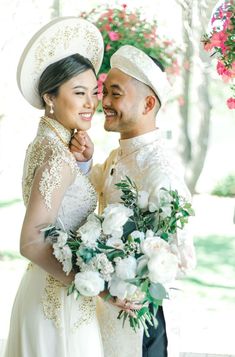 a bride and groom pose for a photo in front of pink flowers on their wedding day