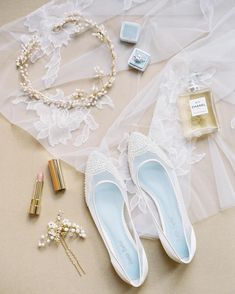 white shoes and accessories laid out on a table next to a veil, perfume bottle, bracelet, and necklace