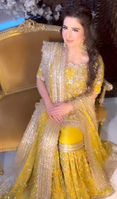 a woman sitting on top of a chair wearing a yellow dress with gold sequins