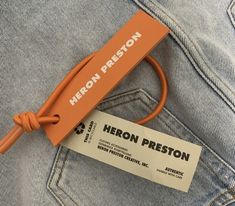 a pair of jeans with an orange label on the back pocket and a cord attached to it