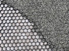 an asphalt surface with hexagonal tiles and small holes in the center, as if it were made out of cement