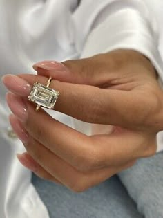 a woman's hand holding a ring with a diamond in the middle and a baguette on it