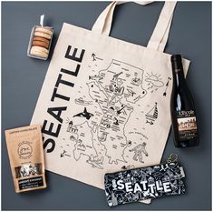 a tote bag with seattle on it next to two bottles of wine and cookies