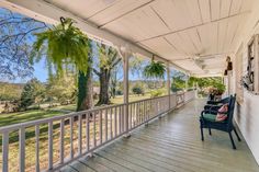 a porch with two chairs on it and trees in the background