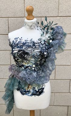 a white mannequin with blue and grey fabric on it