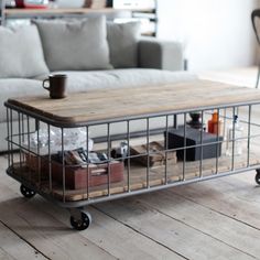 a living room with a couch, coffee table and bookcase on wheels in front of it