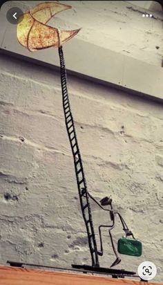 a lamp that is on top of a wooden table next to a brick wall with a ladder going up it