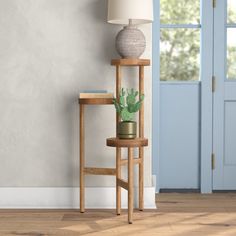 a wooden table with a plant on it next to a blue door and a lamp