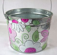 a metal bucket with flowers painted on it