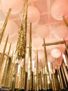 a room filled with lots of balloons and gold foiled objects hanging from the ceiling