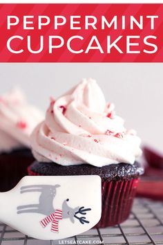 a cupcake with white frosting and red sprinkles on top is sitting on a cooling rack