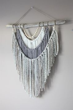 a white wall hanging with beads and tassels on the bottom, along with an iphone