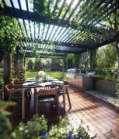 an outdoor dining area with wooden tables and chairs under a pergolated roof, surrounded by greenery