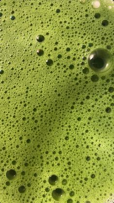 water bubbles on the surface of a green bowl with black circles and white dots in it