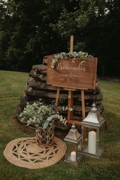 a wooden sign sitting on top of a lush green field next to a candle holder