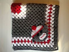 a crocheted blanket with a teddy bear on it and a red, white, and black design