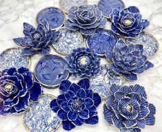 blue and white ceramic flowers on a marble counter top with gold trim around the edges