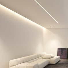 a large white couch sitting in a living room next to a tv mounted on a wall