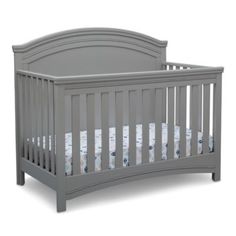 a gray crib with white sheets on it